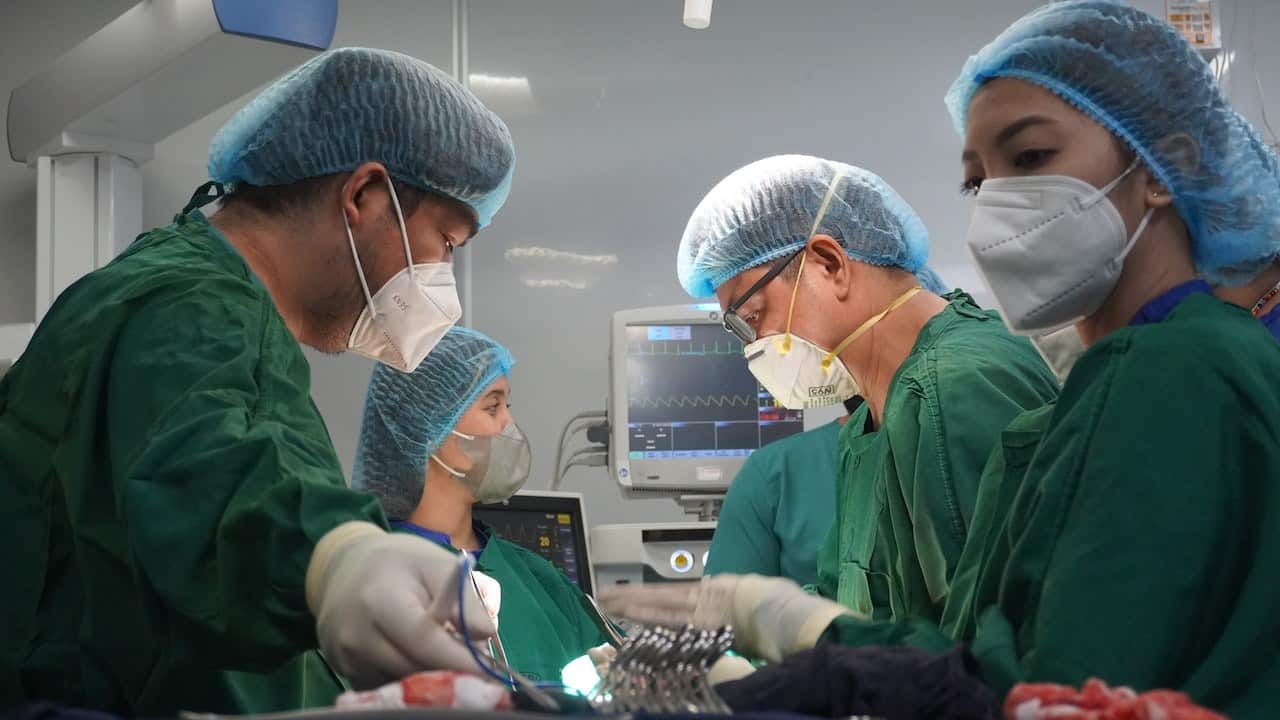 Surgeons focusing on a complex medical procedure with precision and teamwork in a well-lit operating room.